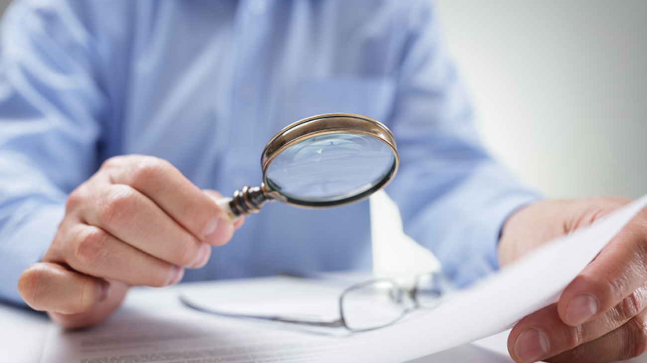 Businessman reading documents with magnifying glass concept for analyzing a finance agreement or legal contract